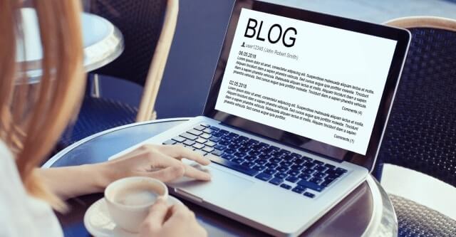 a woman typing up blog content on her laptop with coffee